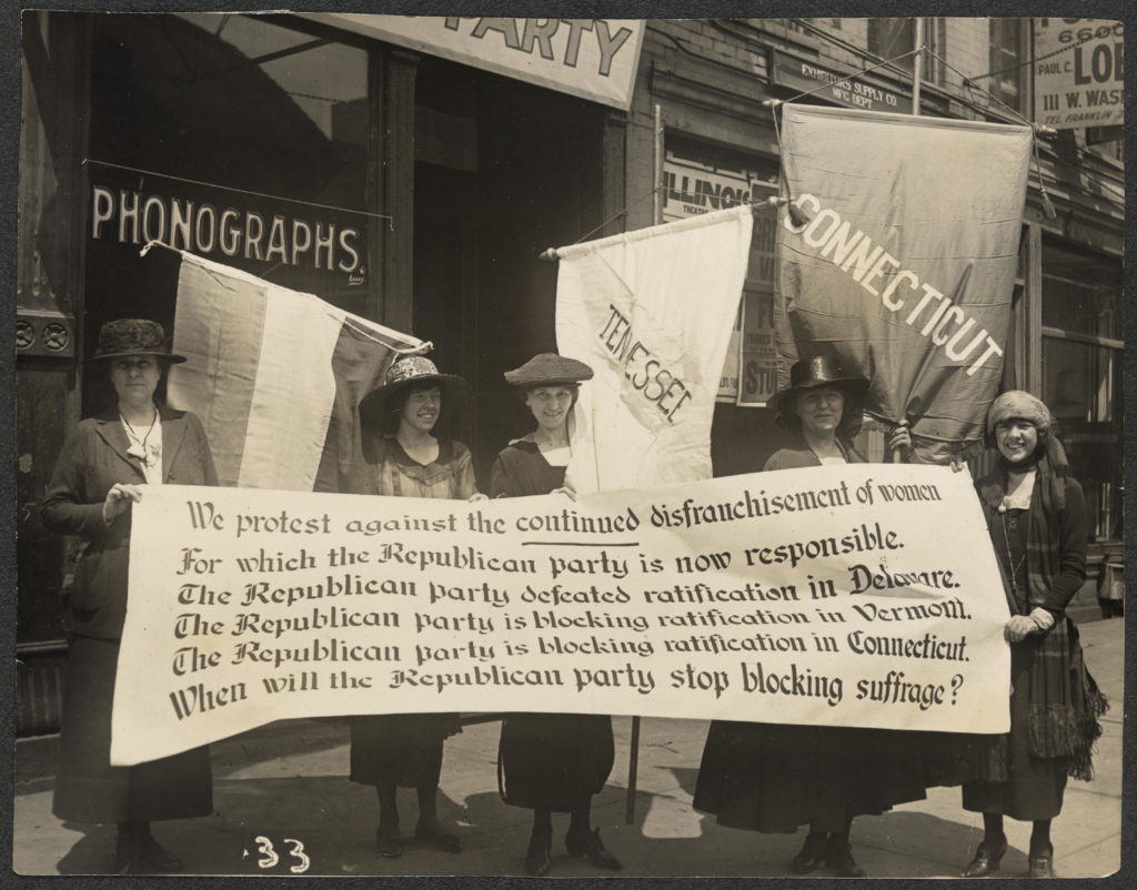 National Woman's Party members holding a sign that says "we protest against the continued disfranchisement of women for which the Republican party is now responsible. The Republican party defeated ratification in Delaware. The Republican party is blocking ratification in Vermont. The Republican party is blocking ratification in Connecticut. When will the Republican party stop blocking suffrage?